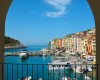 Pohľad na farebné domy pri prístave s loďami v Portovenere cez oblúk.