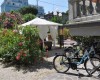 Bicykle opreté o kamenný múr vedľa záhradného altánku obklopeného kríkmi.