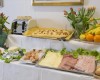 Raňajkový bufet s výberom údenín, syrov, zeleniny, pečiva, ovocia a váz s tulipánmi.