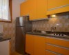 Malá kuchyňa s oranžovými skrinkami a retro obkladom.