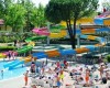 Aquapark so šmykľavkami, bazénom a ľuďmi odpočívajúcimi na ležadlách.