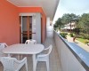 Balkón s bielym plastovým stolom a stoličkami vedľa oranžovej steny s výhľadom na zeleň.  