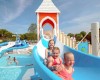 Deti sa spúšťajú na modrej šmykľavke do bazéna na vodnom ihrisku.