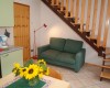 Obývacia izba s pohovkou, schodiskom a jedálenským stolom s vázou slnečníc.