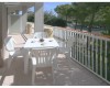 Priestranný balkón s plastovým stolom, štyrmi stoličkami a šálkami.