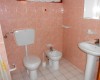 Kúpeľňa s toaletou, bidetom a umývadlom, obložená ružovými kachličkami.