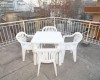 Biely plastový jedálenský stôl so štyrmi stoličkami na terase.