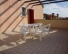 Plastový stôl so štyrmi stoličkami na strešnej terase s dlažbou.