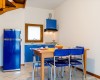 Kuchyň s modrými skrinkami a stoličkami okolo dreveného stola.
