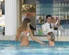Žena a dieťa v plavkách pri bazénovom bare, barman mieša nápoje.