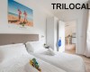 Svetlá izba s dvoma posteľami, plagátom na stene a nápisom TRILOCALE.