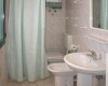 Kúpeľňa s umývadlom, toaletou a sprchovým kútom so závesom.