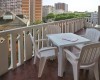 Plastový stôl a stoličky na balkóne s výhľadom na mestskú zástavbu.