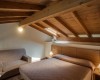 Podkrovná spálňa s dreveným stropom, manželskou posteľou a pohovkou.