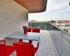 Balkón s červenými stoličkami, stolom a kvetináčom s rastlinou.