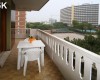 Balkón s bielym plastovým stolom a stoličkami s výhľadom na mestské budovy.