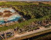 Letecký pohľad na rekreačný areál s bazénmi a stromami obklopený krajinou.
