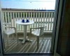 Balkón s plastovým stolíkom, dvoma stoličkami a výhľadom na more.