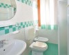 Kúpeľňa s umývadlom, toaletou, bidetom a sprchovacím kútom s tyrkysovým obkladom.