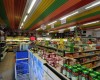 Interiér obchodu s barevným stropom a plnými regálmi potravín.