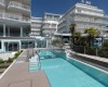 Moderný hotel s vonkajším bazénom a palmami.