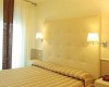 Svetlá spálňa s čalúneným čelom postele a dvoma nástennými lampami.