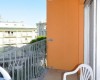 Balkón s oranžovými stenami, plastovou stoličkou a výhľadom na okolité budovy.