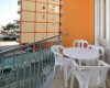 Balkón s plastovým stolom a stoličkami, výhľad na oranžovú budovu.