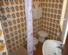 Kúpeľňa s retro kvetinovými dlaždicami, sprchovým kútom, umývadlom a toaletou.  