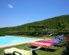 Slnečné lehátka okolo bazéna s výhľadom na zalesnené kopce.
