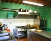 Kuchyňa s kovovým nábytkom, sporákom a zelenými stenami.  