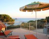Terasa s ležadlami a slnečníkom s výhľadom na more a ostrov.
