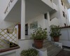 Vstup do bielej budovy so schodmi a kvetináčmi.