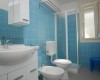 Modrá dlažba v kúpeľni so sprchovacím kútom, umývadlom, toaletou a bidetom.
