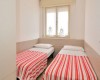 Dve jednolôžkové postele s červeno-bielymi pruhovanými prehozmi v malej miestnosti.