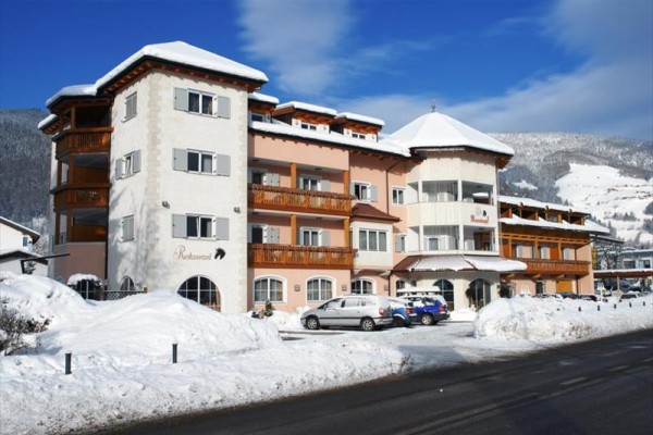 Hotel v zasneženej horskej krajine s modrou oblohou.