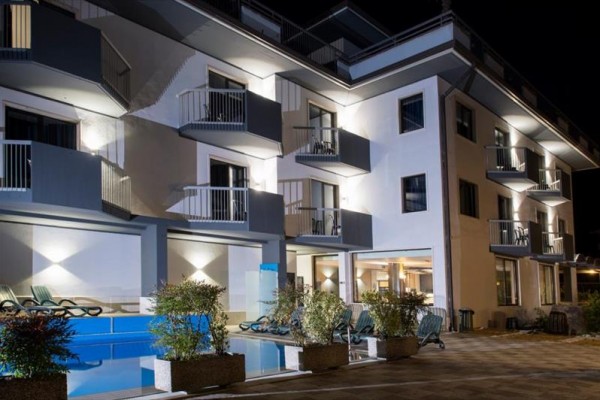 Moderný hotel s terasami osvetlený v noci.