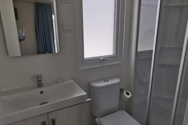 Malá kúpeľňa so sprchovacím kútom, umývadlom a toaletou.