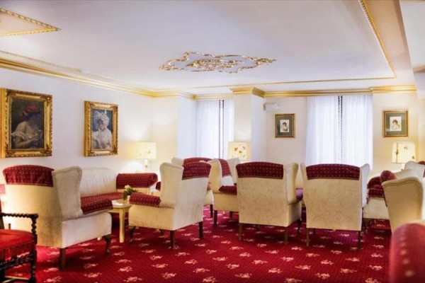 Elegantný obývací priestor s červenými a krémovými kreslami a obrazmi na stenách.
