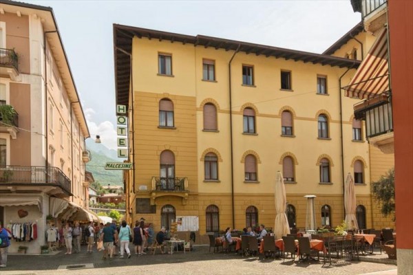 Starý hotel s vonkajšou kaviarňou na námestí.