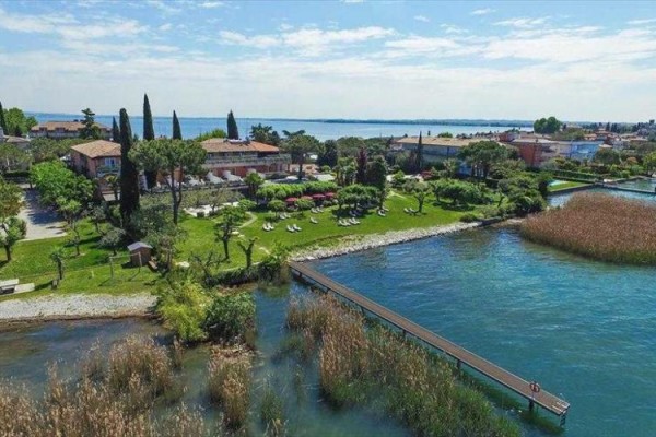 Pohľad na zelený park s budovami pri jazere a dreveným mólem.