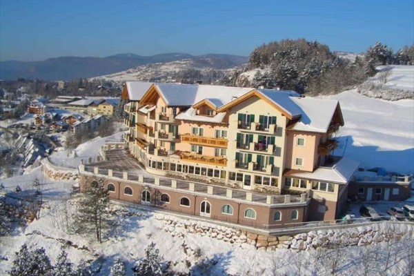 Veľký hotel s farebnými fasádami v zasneženej horskej krajine.