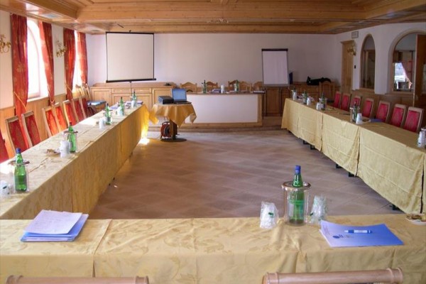 Konferenčná miestnosť s rozostavenými stolmi, stoličkami a projektorom.