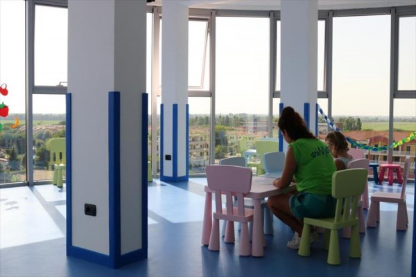 Dve osoby sedia pri malom stole v detskom centre s výhľadom na mesto.