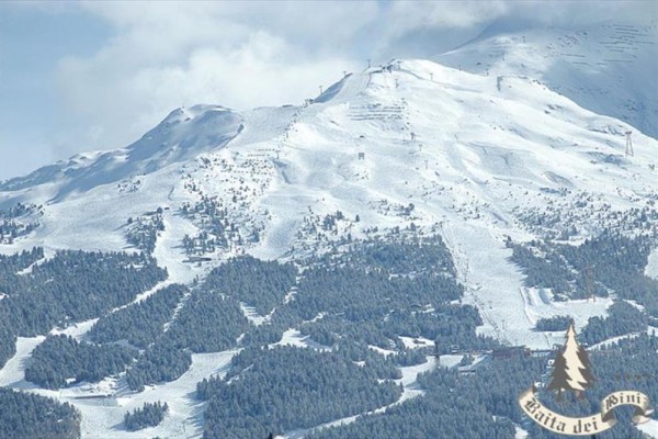 Zasnežená horská krajina s lesmi a zjazdovkami na svahu.