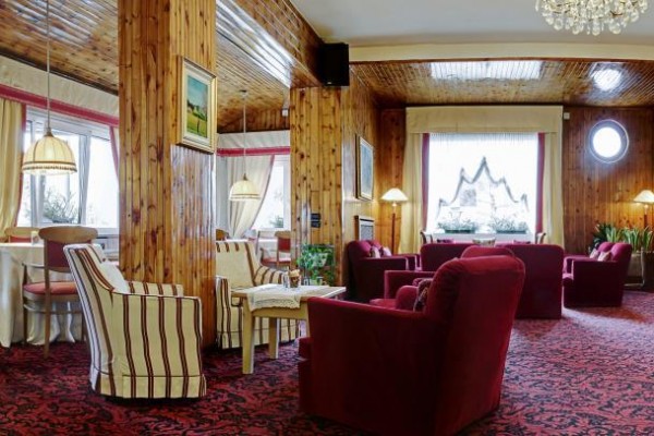 Elegantná hotelová lounge s červenými kreslami a dreveným obložením.