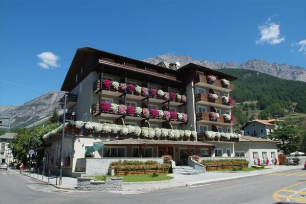 Hotel so zdobenými balkónmi kvetmi na pozadí hôr a lesa.  