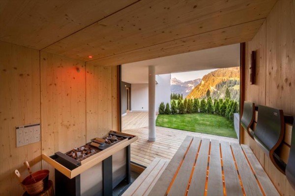 Sauna s výhľadom na hory a terasu so zeleným trávnikom.