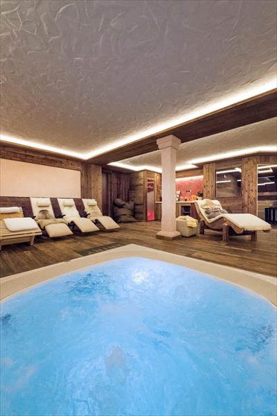 Wellness miestnosť s vírivkou a ležadlami.