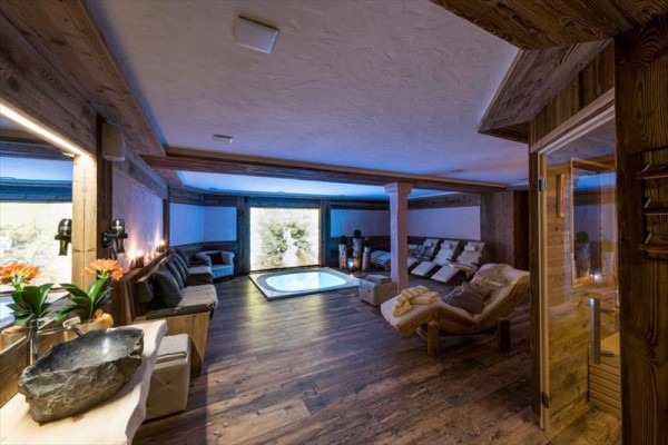 Luxusná wellness miestnosť s vírivkou, ležadlami a dreveným obložením.